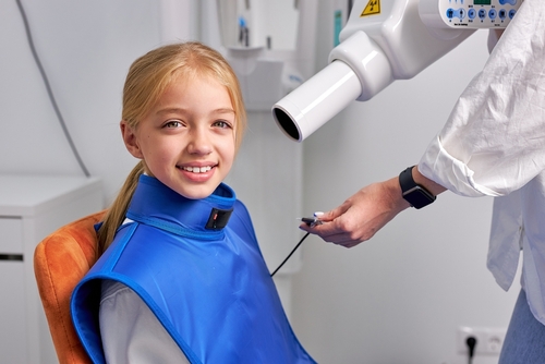 Young,Child,Girl,Next,To,Dental,3d,X-ray,Digital,Scanner X-Rays - Kid Grins